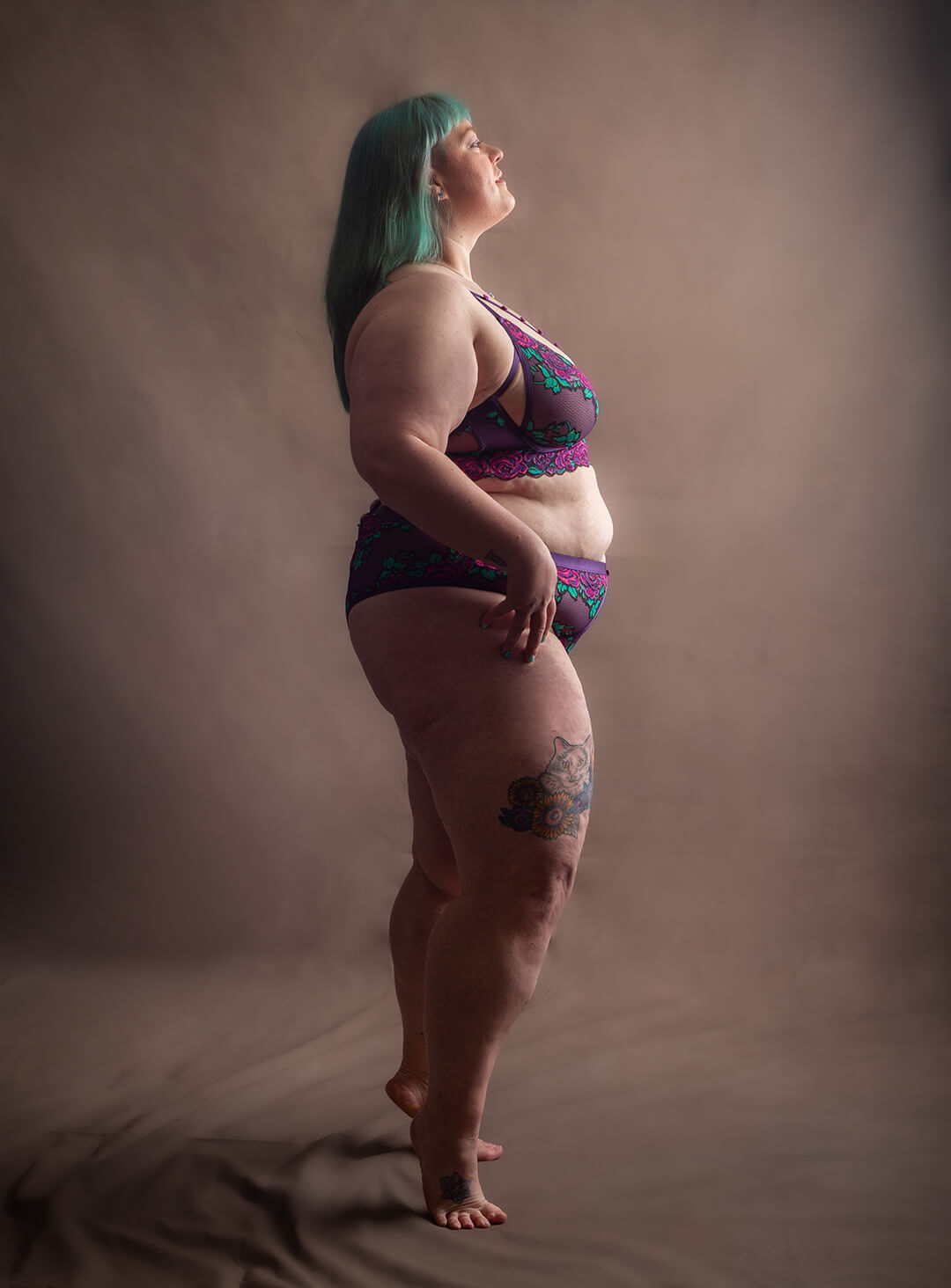 Plus size person with turquoise coloured hair, on tip toes in fushia pink underwear